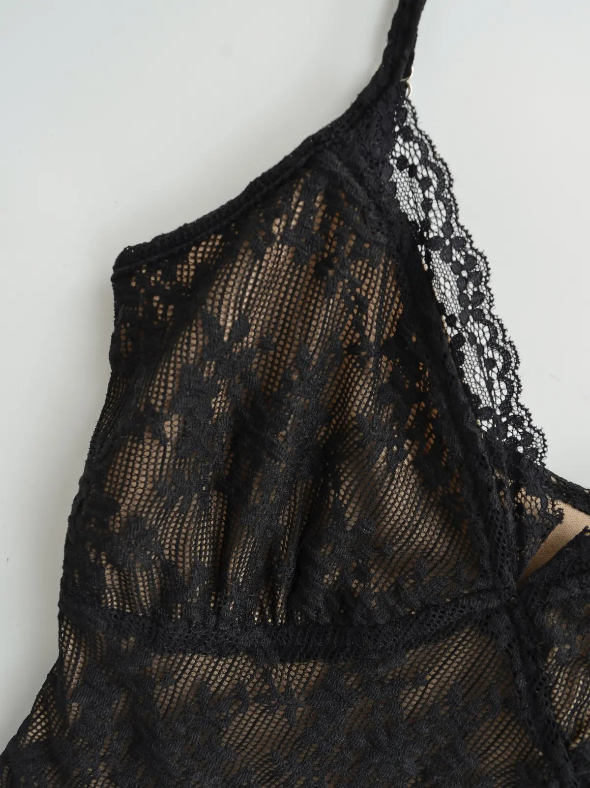 Close-up of the V-neckline and lace strap detail on the black cami top