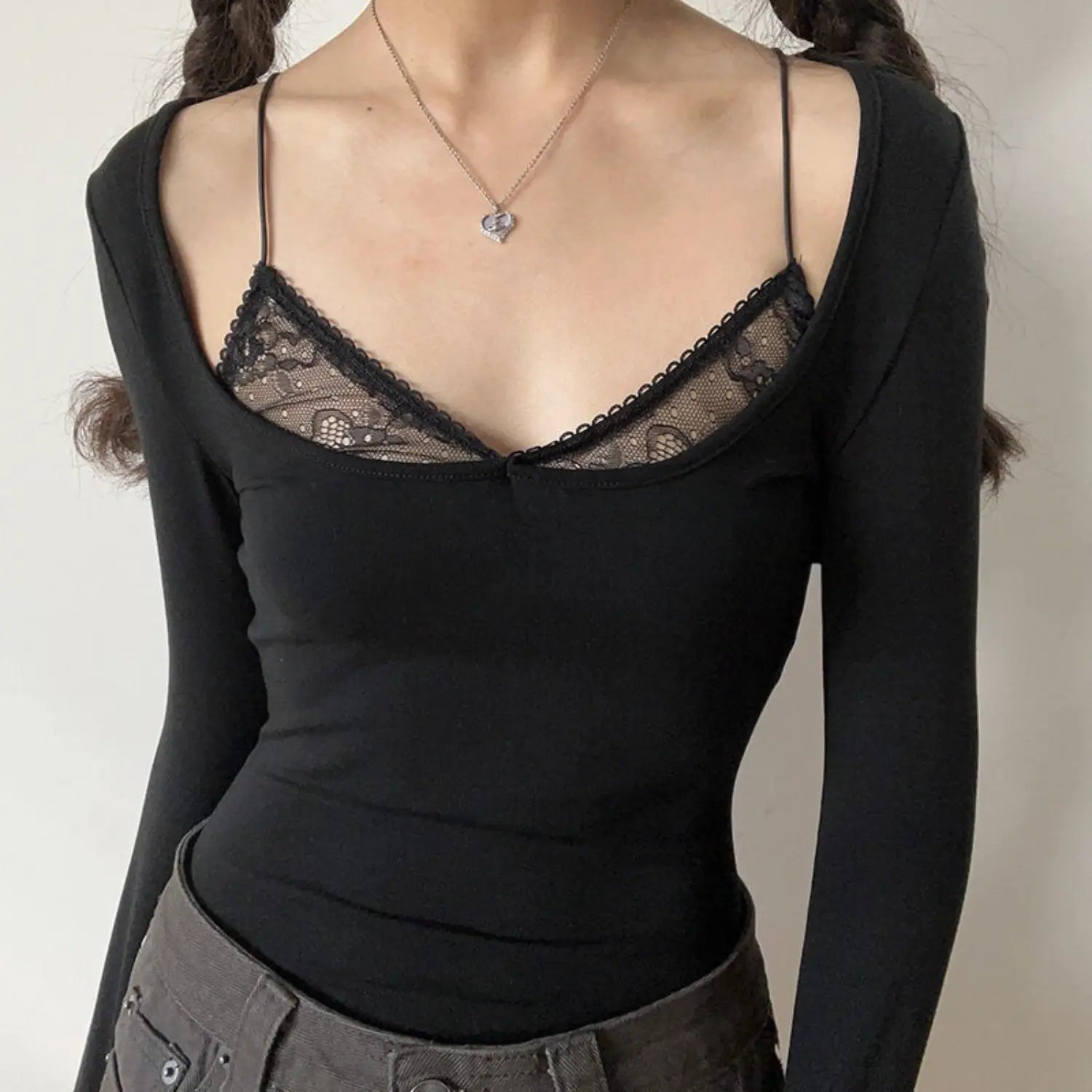 Black lace fake two piece u neck long sleeve top half body indoor model shot, wide u neck with inner black lace thin straps, soft stretch fabric slim waist cropped fit, matched with grey casual pants cool feminine outfit