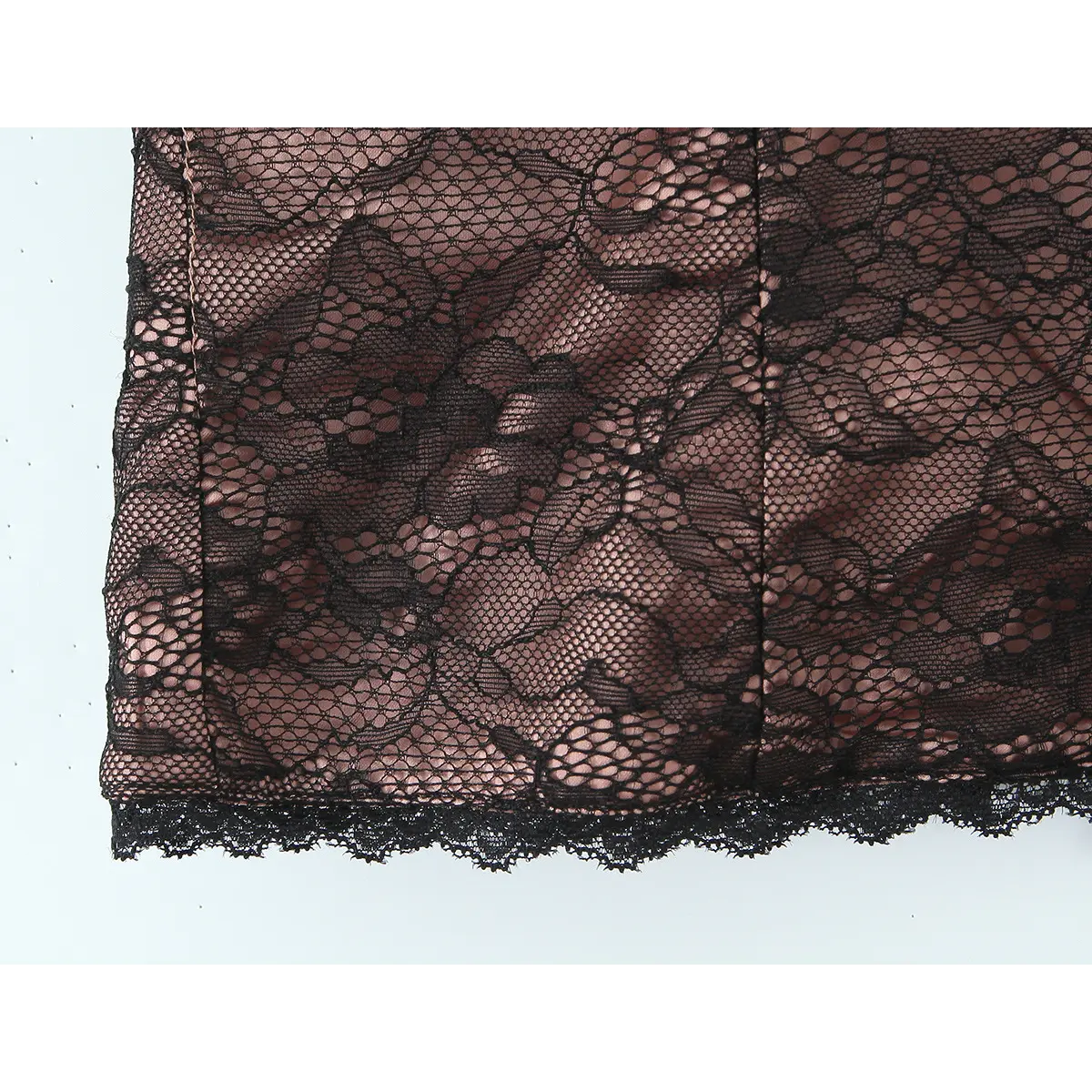 Close-up of the vertical boning seams and floral lace overlay on the bustier.
