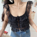  Front view of a woman wearing a black layered lace camisole with a front tie and buttons, paired with jeans.