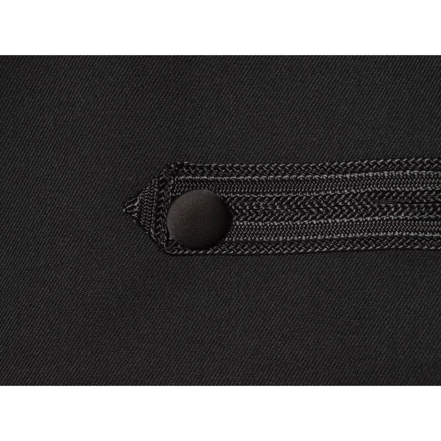 Macro shot of fabric‑covered button and woven braid trim detail on black cropped military jacket