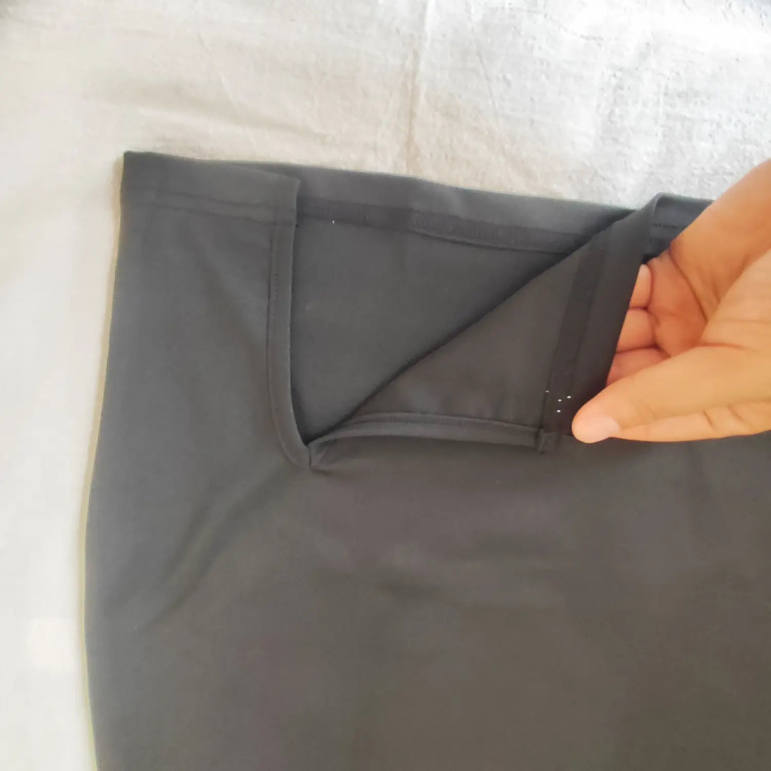 Close‑up inner fabric and stitching of waist cutout opening on black bodycon mini skirt
