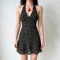 Model wearing a black halter-neck mini dress with a multi-color floral print, lace trim at the neckline, and a deep V-neck.