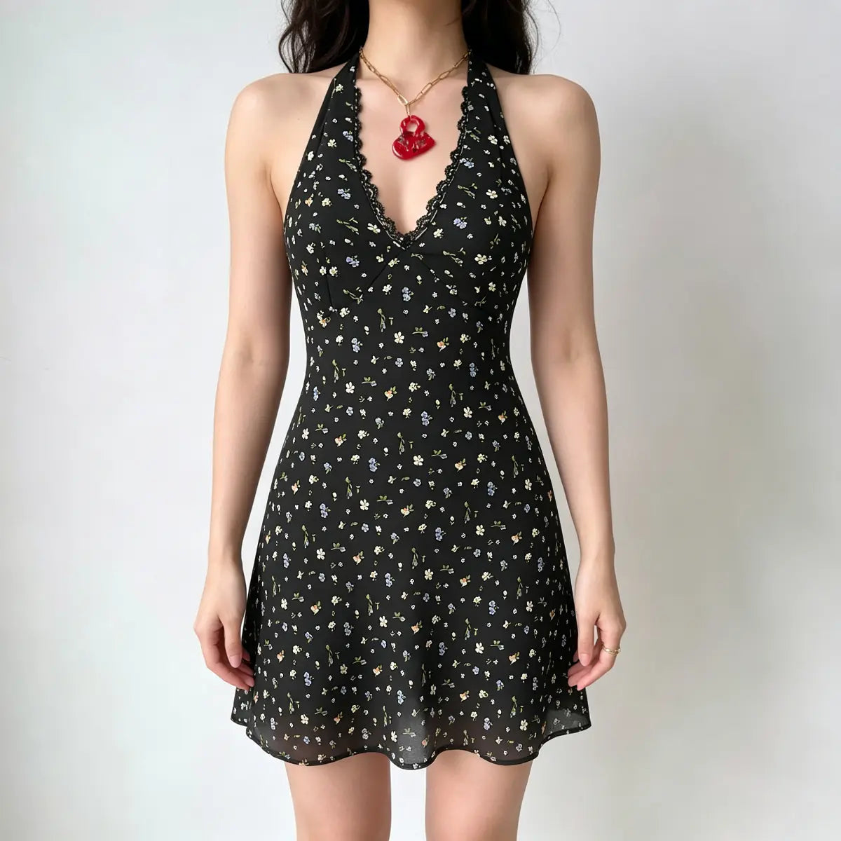 Model wearing a black halter-neck mini dress with a multi-color floral print, lace trim at the neckline, and a deep V-neck.