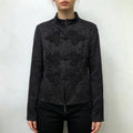 Model wearing black new chinese cropped jacket, decorative frog buttons, mandarin collar, floral jacquard fabric, front styling shot