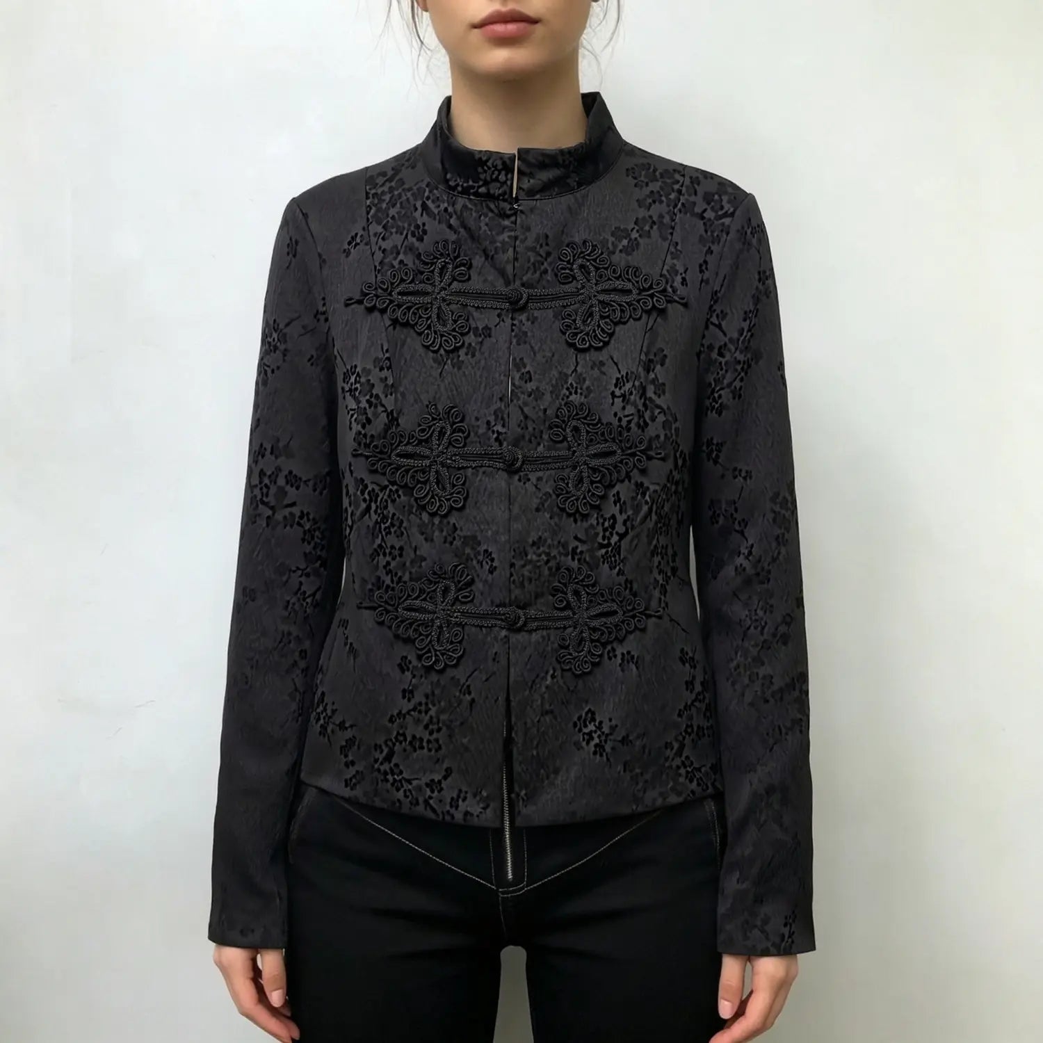 Model wearing black new chinese cropped jacket, decorative frog buttons, mandarin collar, floral jacquard fabric, front styling shot