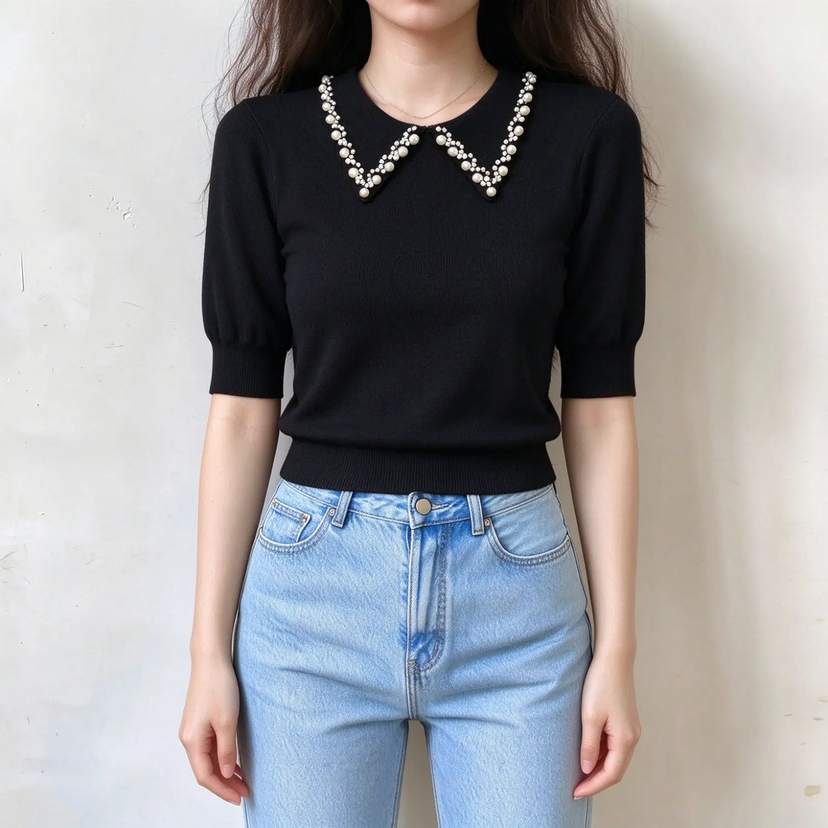 Model wearing black pearl collar knit top with jeans, front view