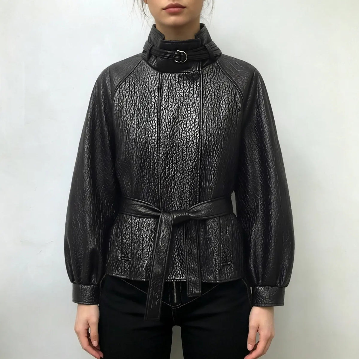 Model wearing black pebbled leather look jacket with stand collar and belted waist