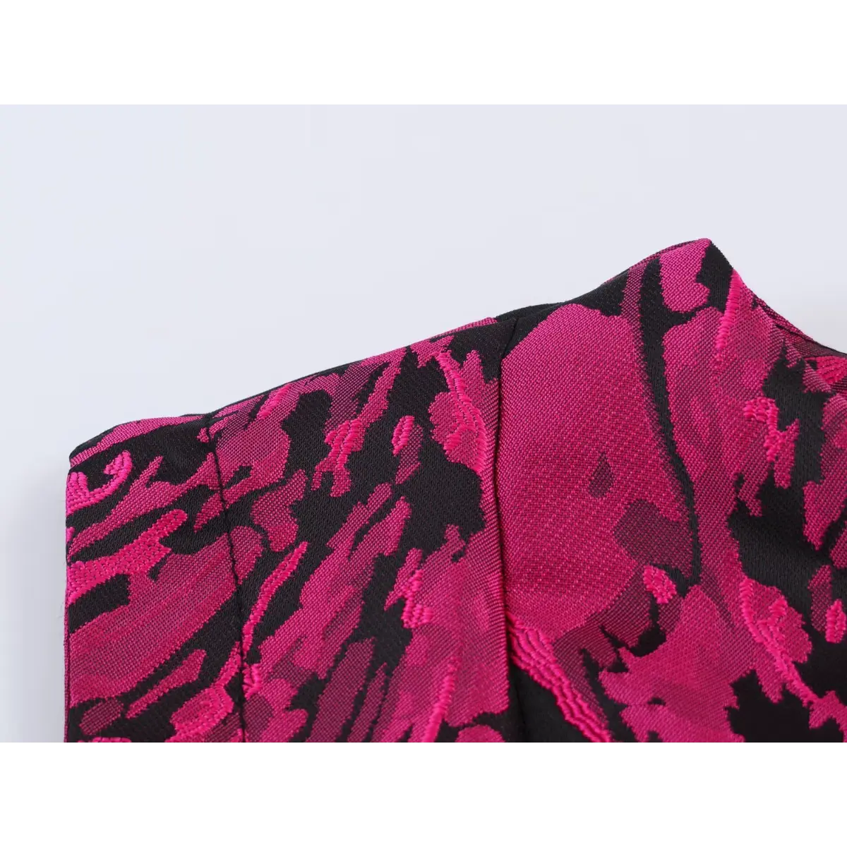 Close-up of the dress shoulder seam, showing the tailored construction and floral jacquard pattern