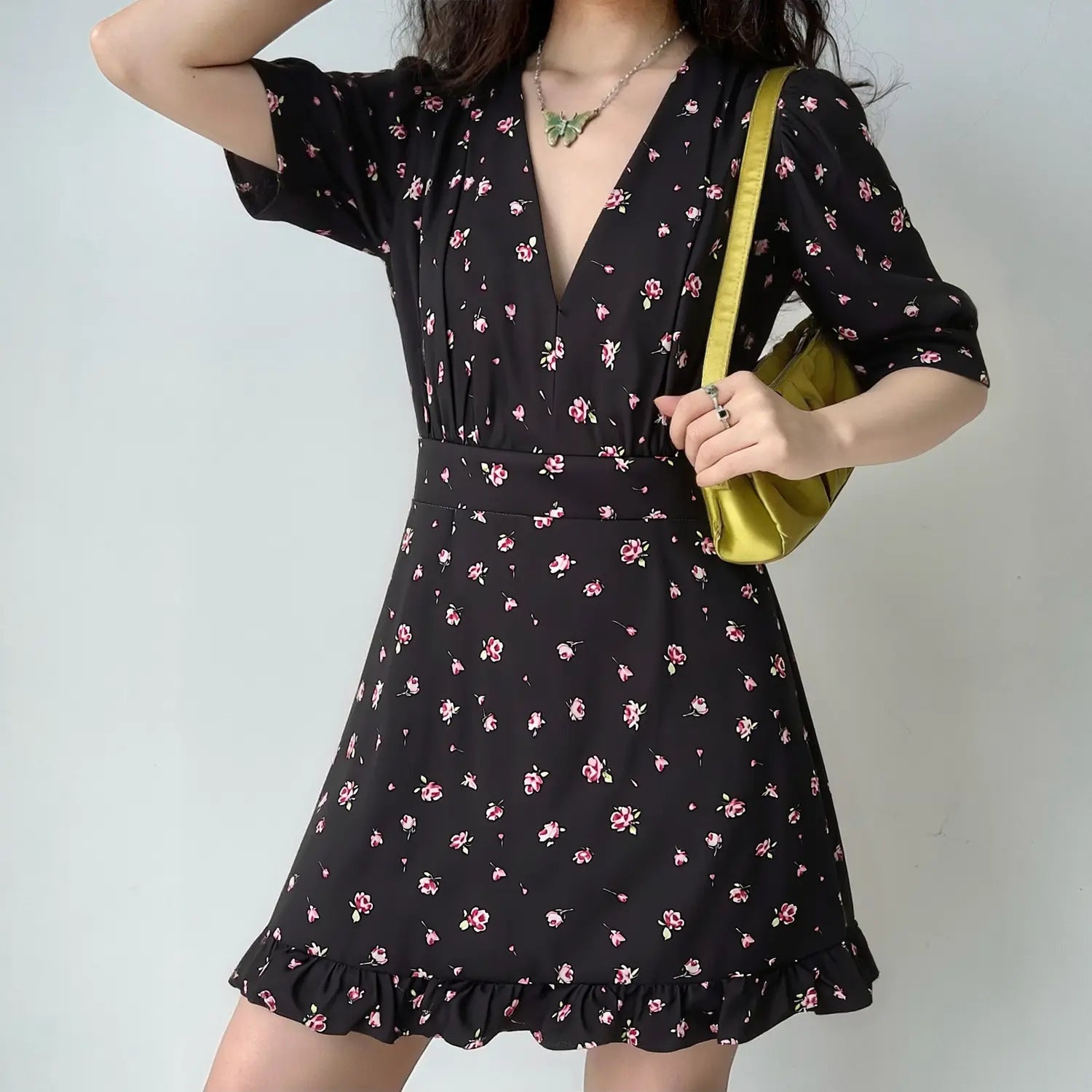 Lifestyle model photo, woman wearing black pink ditsy floral V-neck mini dress