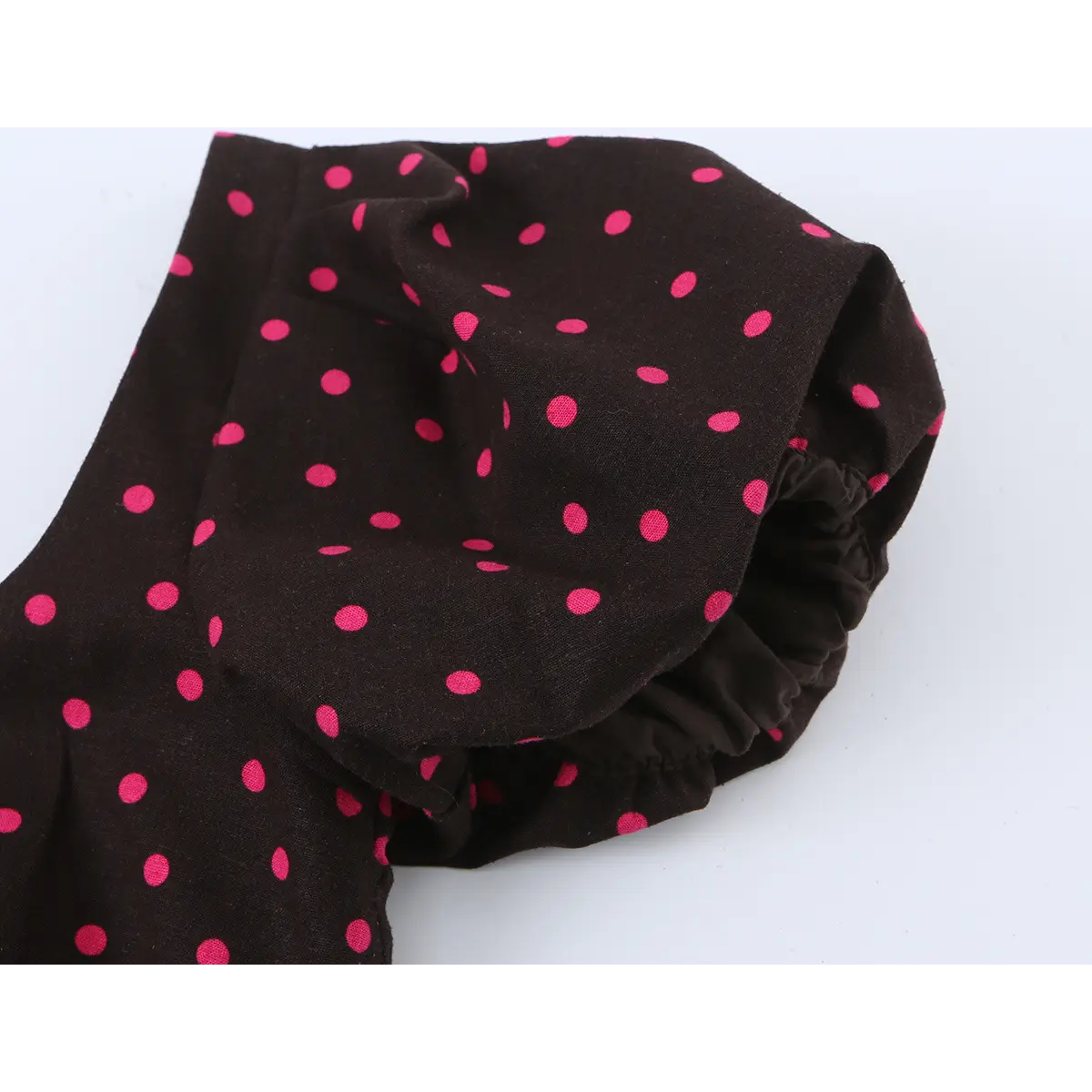 Close-up of the dress's puff sleeve, showing the gathered elastic cuff and pink polka dot print on black fabric.