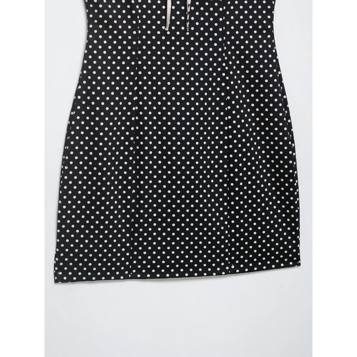 Close-up of the flared hem and lightweight fabric texture on the black polka dot cami dress