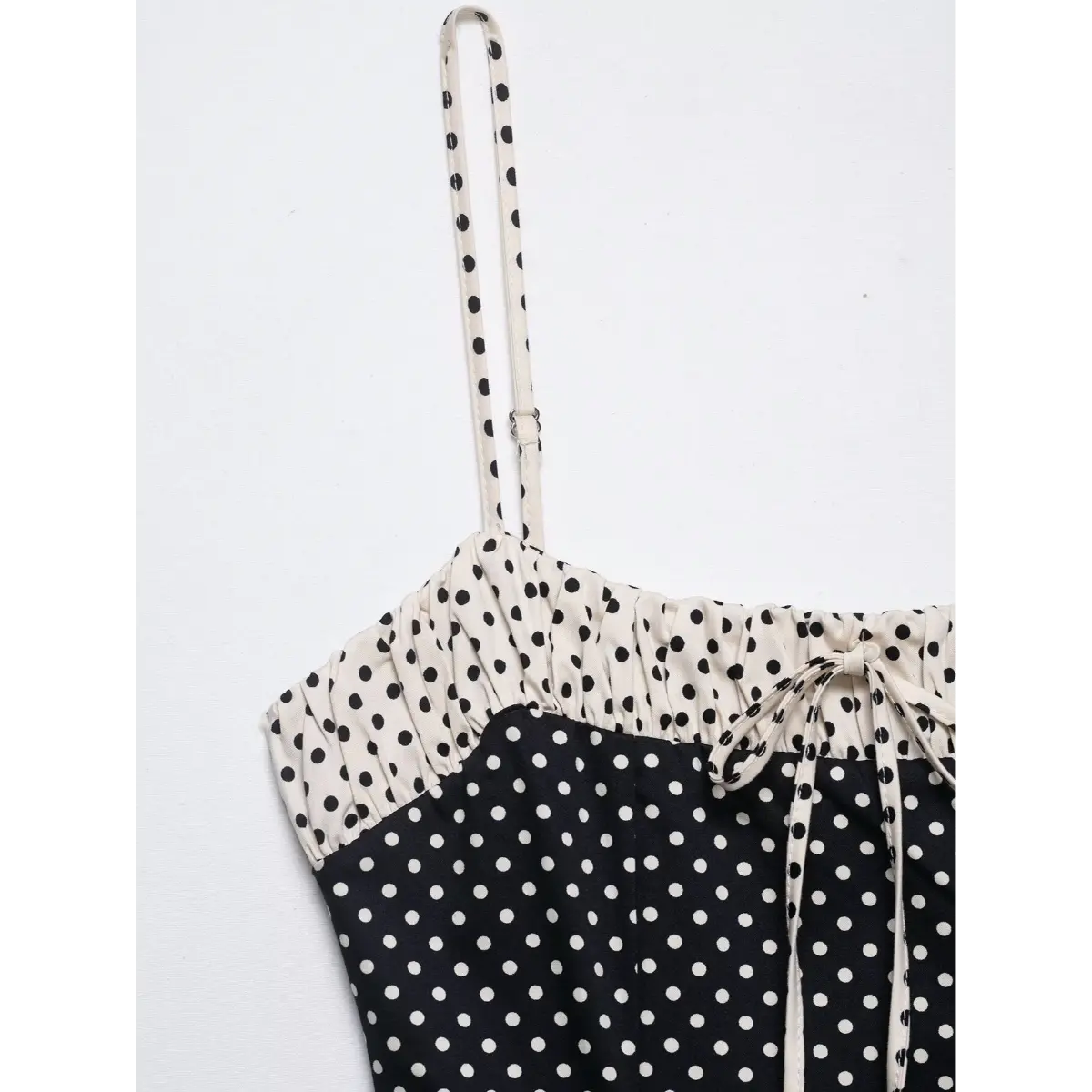 Close-up of the spaghetti straps and lace-trimmed bustline on the black polka dot cami dress