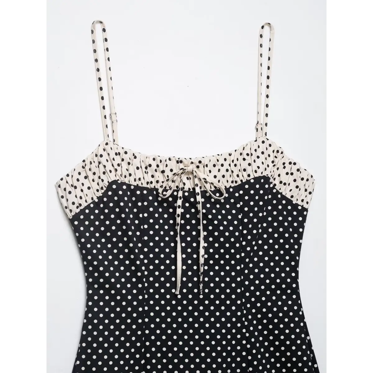 Close-up of the front tie detail and gathered bust on the black polka dot cami dress