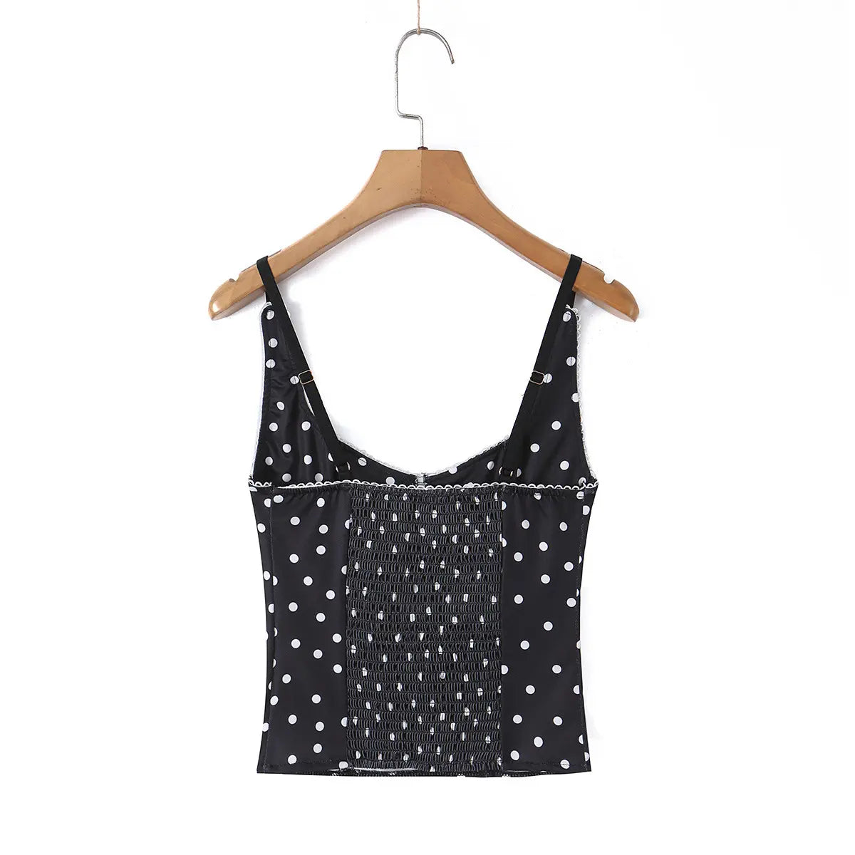 Black polka dot cami top hanging on wooden hanger, full back view