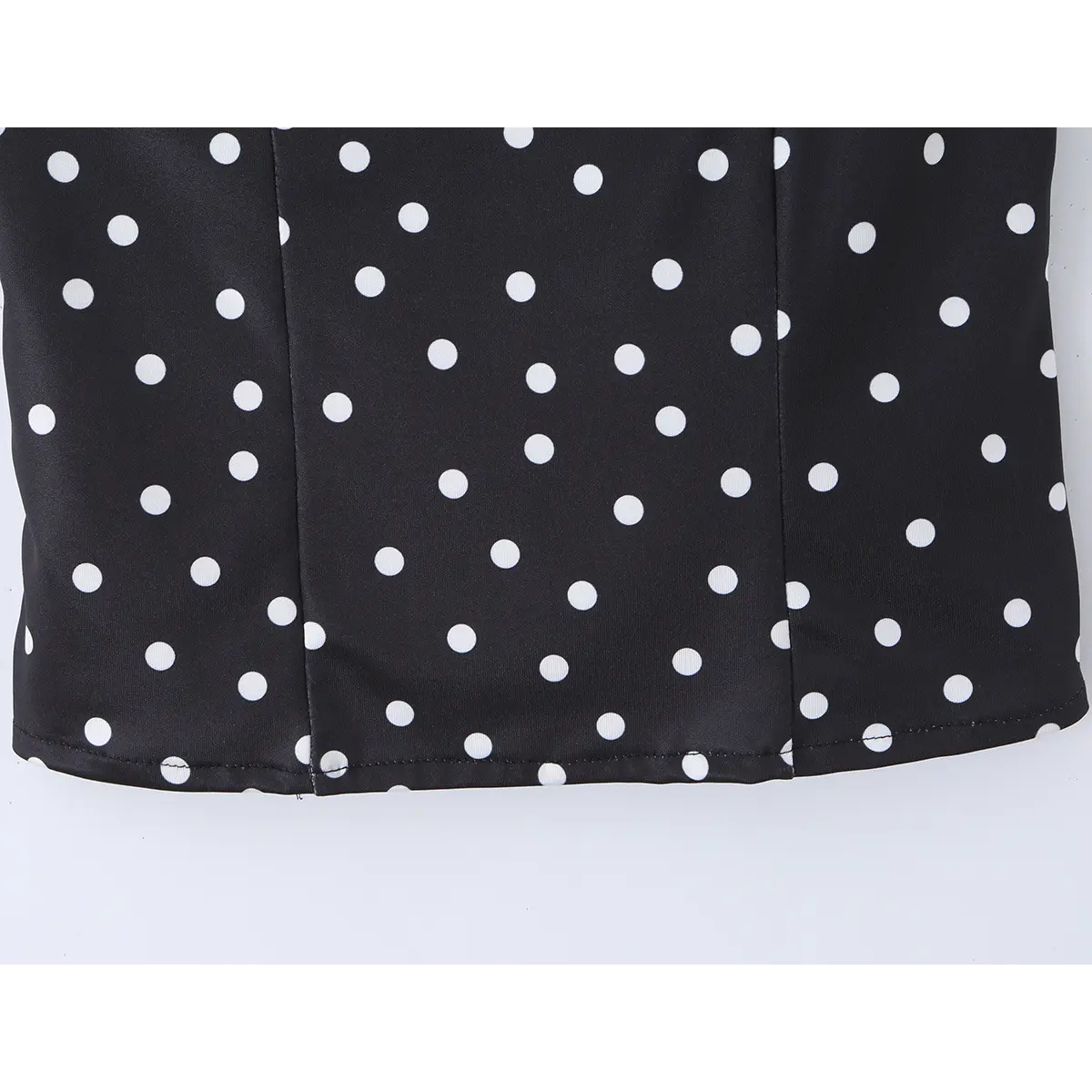 Close-up of the tailored side seams and polka dot print on the black cami top