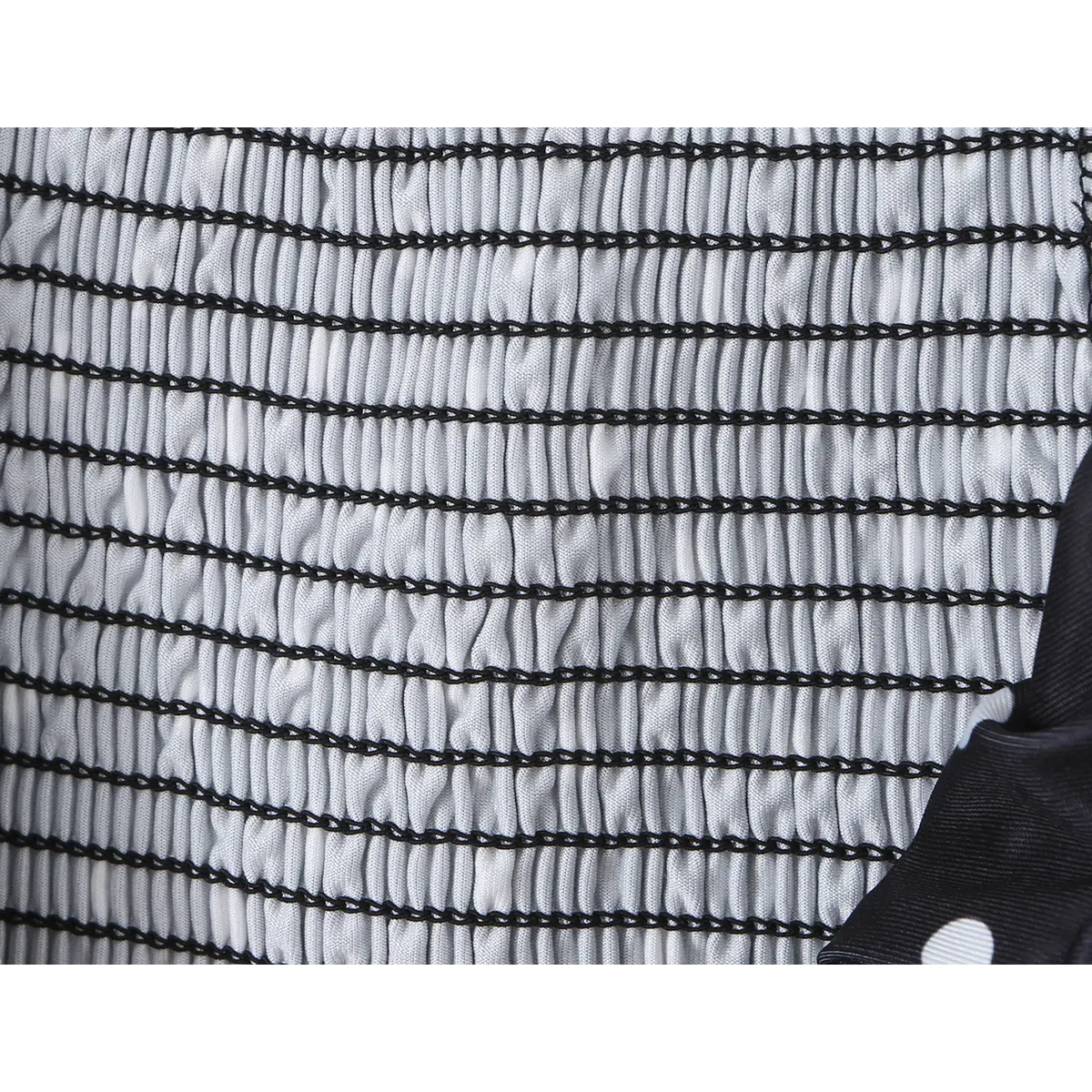 Close-up of the elastic smocked fabric texture on the black cami top