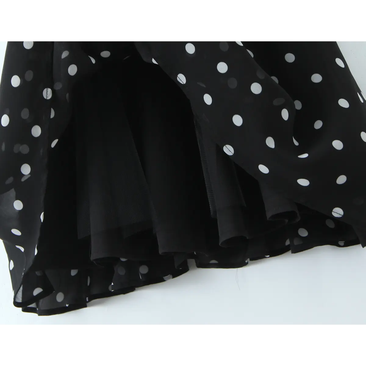 Close-up of the layered skirt hem, revealing the flowy chiffon overlay and solid black underlining.