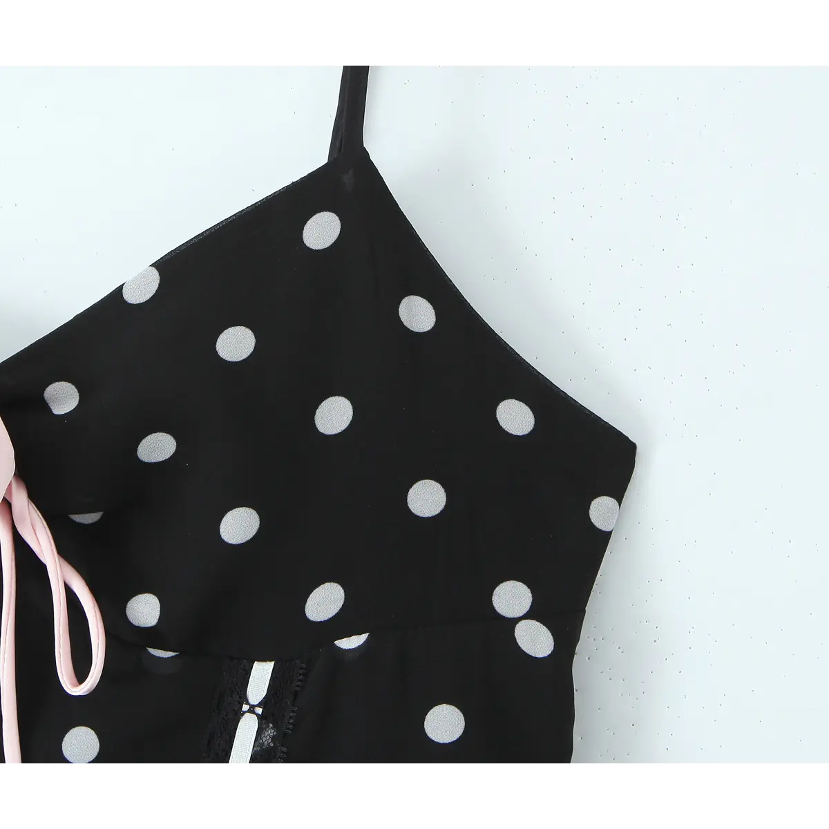 Close-up of the spaghetti strap and sweetheart neckline on the black polka dot dress, showing the pink rose appliqué detail.