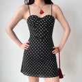 The black polka dot dress styled on a model, highlighting its corset fit, sweetheart neckline, and how it pairs with accessories.