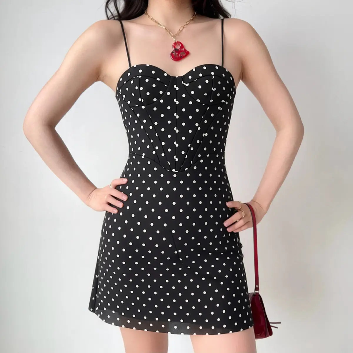 The black polka dot dress styled on a model, highlighting its corset fit, sweetheart neckline, and how it pairs with accessories.