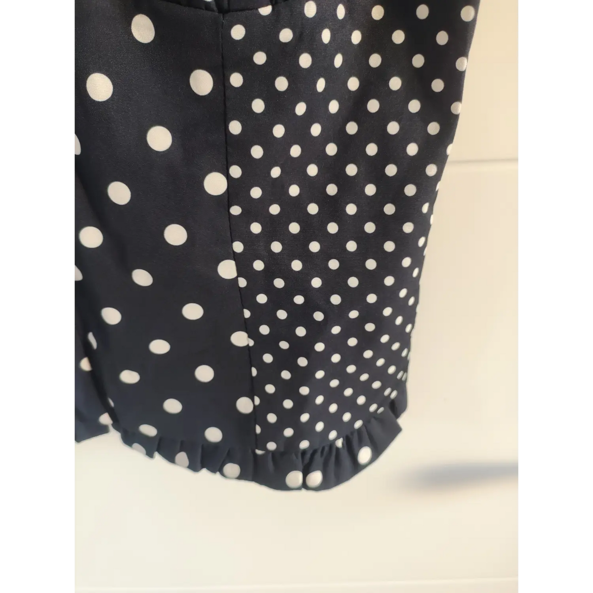 Fabric close‑up showing mixed‑size polka dots and ruffled bottom hem