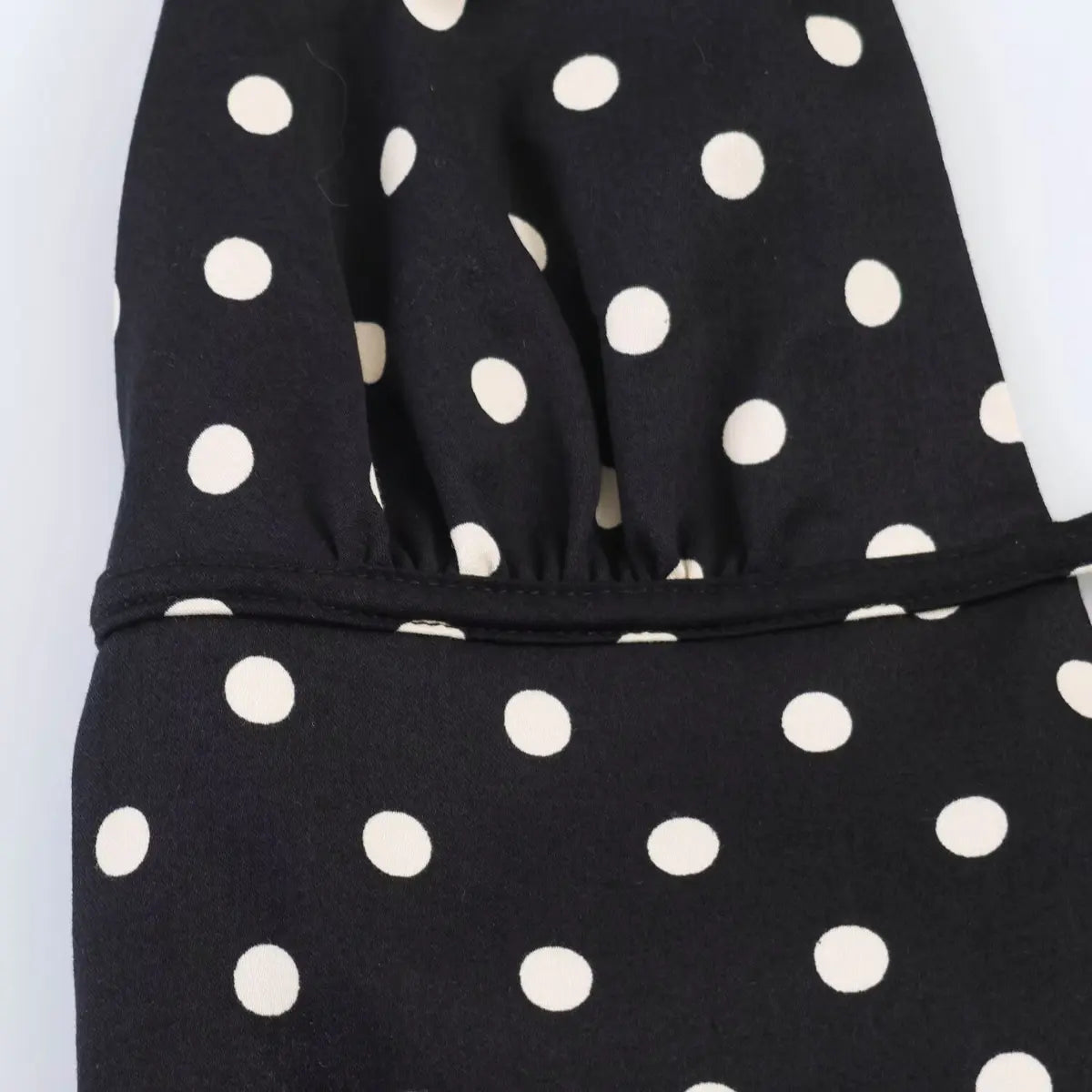 Close-up of the gathered bust area on black polka dot dress, showing pleated fabric and cutout detail.