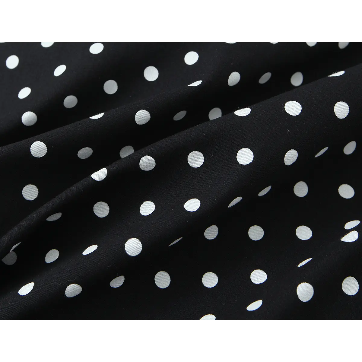 Close-up of the dress's outer fabric, highlighting the smooth surface, polka dot print, and soft drape.