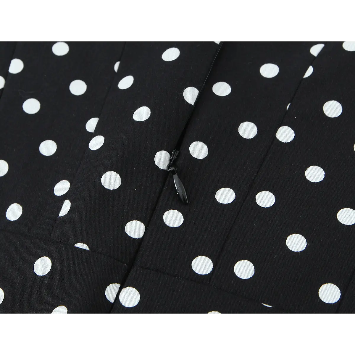 Close-up of the dress's hidden side zipper, featuring a matching black pull tab that blends with the polka dot fabric