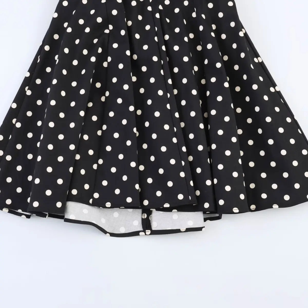 Full view of the flared skirt on black polka dot halter dress, showing layered fabric and inner lining.