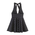 Full front view of black polka dot halter dress, showing deep V-neck, cutout detail and flared skirt.