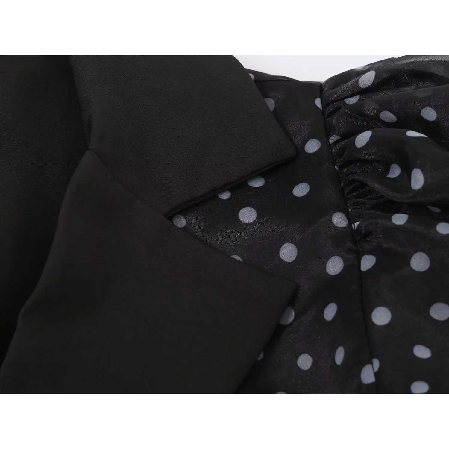 Close‑up lapel collar stitching and shoulder seam detail of black polka dot maxi dress