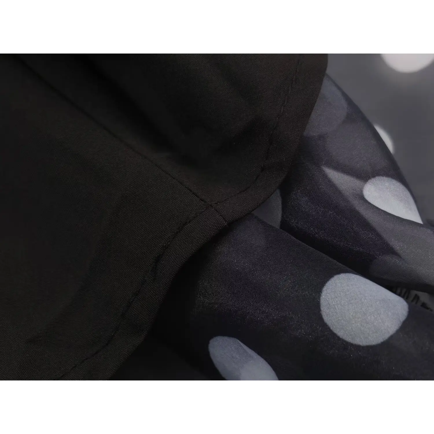 Close‑up lapel collar seam stitching detail of black polka dot maxi dress