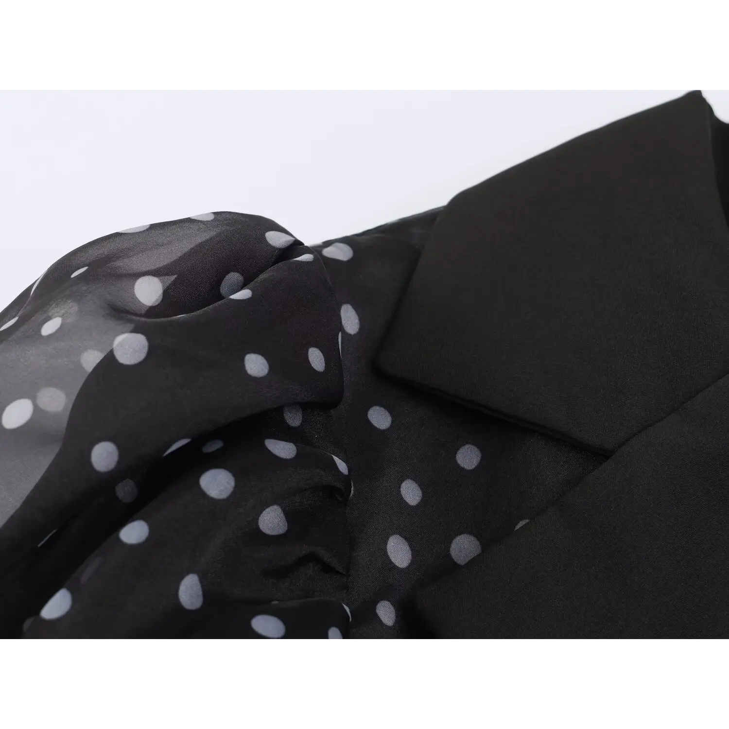 Close‑up sheer organza fabric texture with white polka dots and lapel collar detail