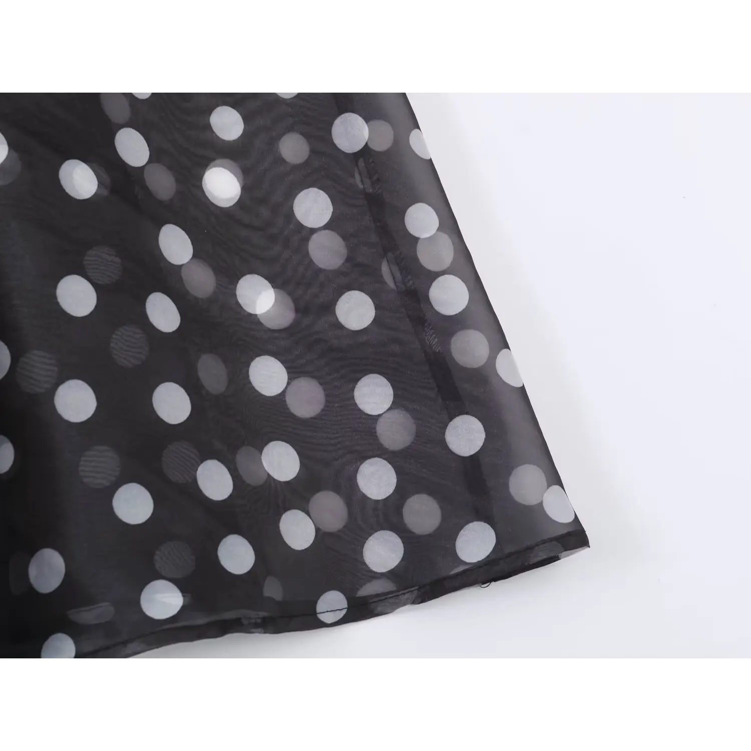 Close‑up finished hem stitching detail on black polka dot organza maxi dress