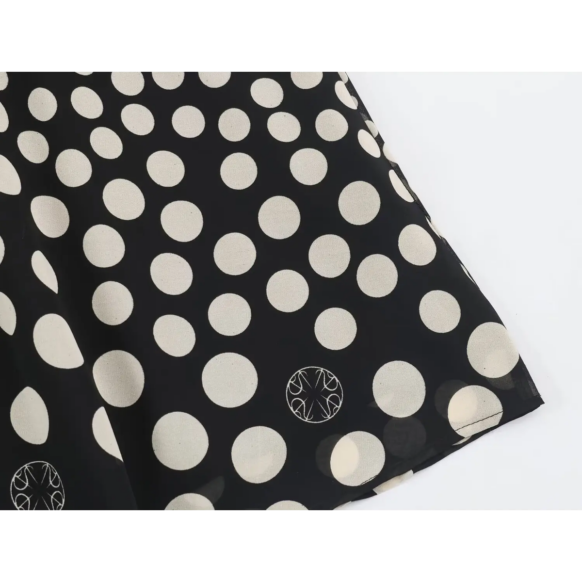 Close-up of irregular white polka dot print on black chiffon maxi dress skirt