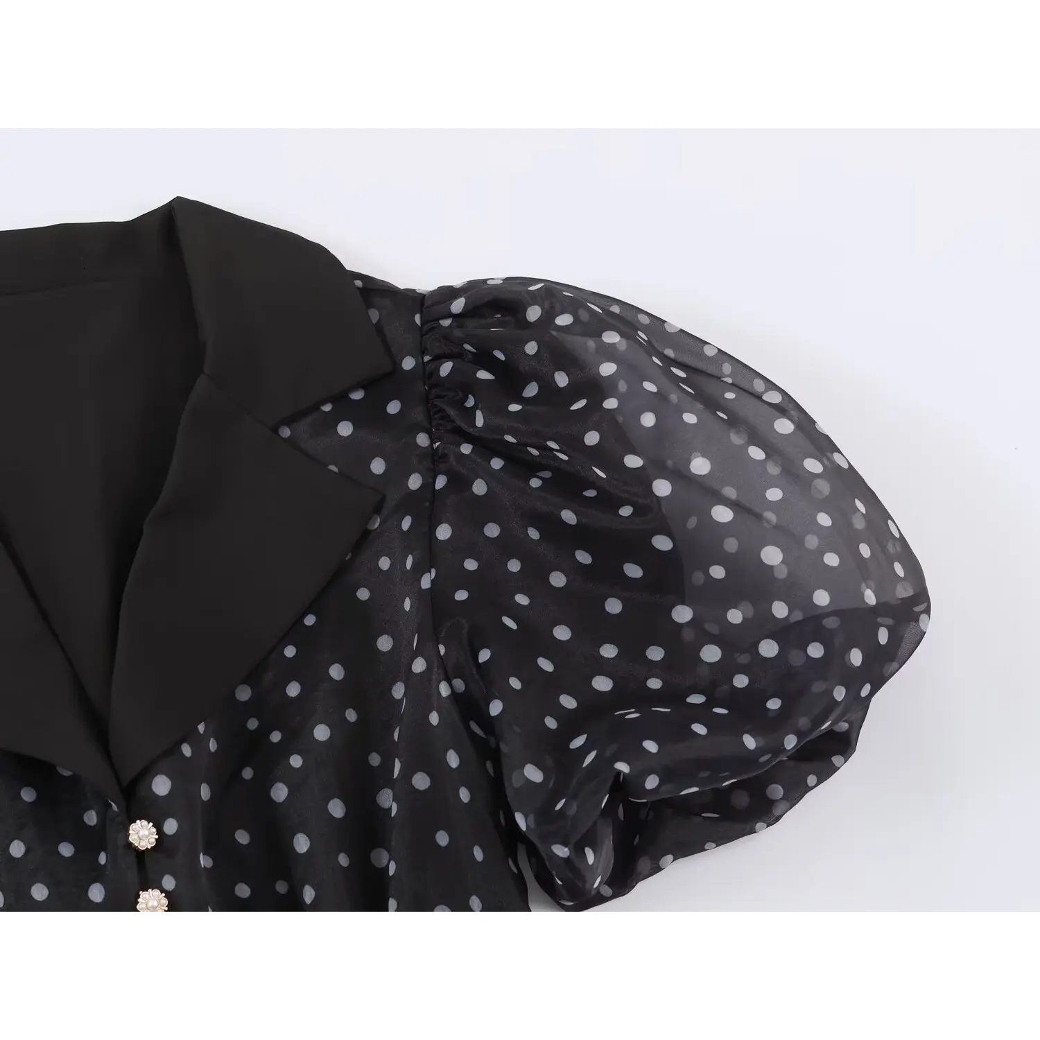 Close‑up of sheer organza puff short sleeve, gathered shoulder on black polka dot maxi dress