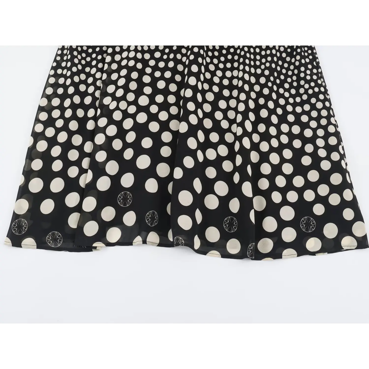 Overhead view of flowy skirt hem on black polka dot maxi dress