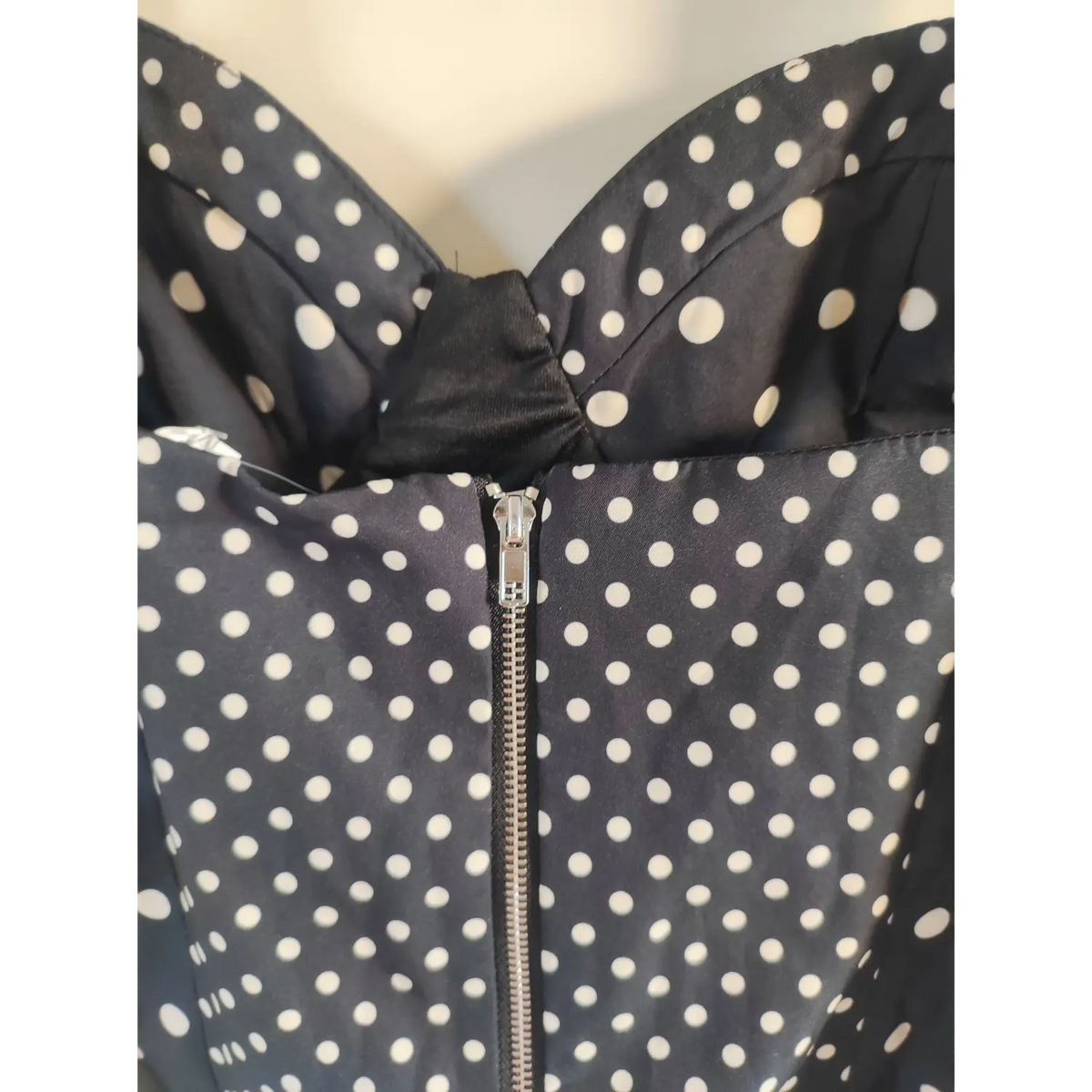 Macro detail of silver metal back zipper on black polka dot crop top