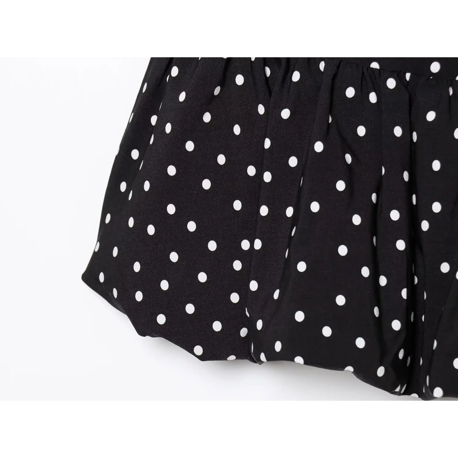 Close‑up ruffle hem gathering and fabric texture black white polka dot short dress
