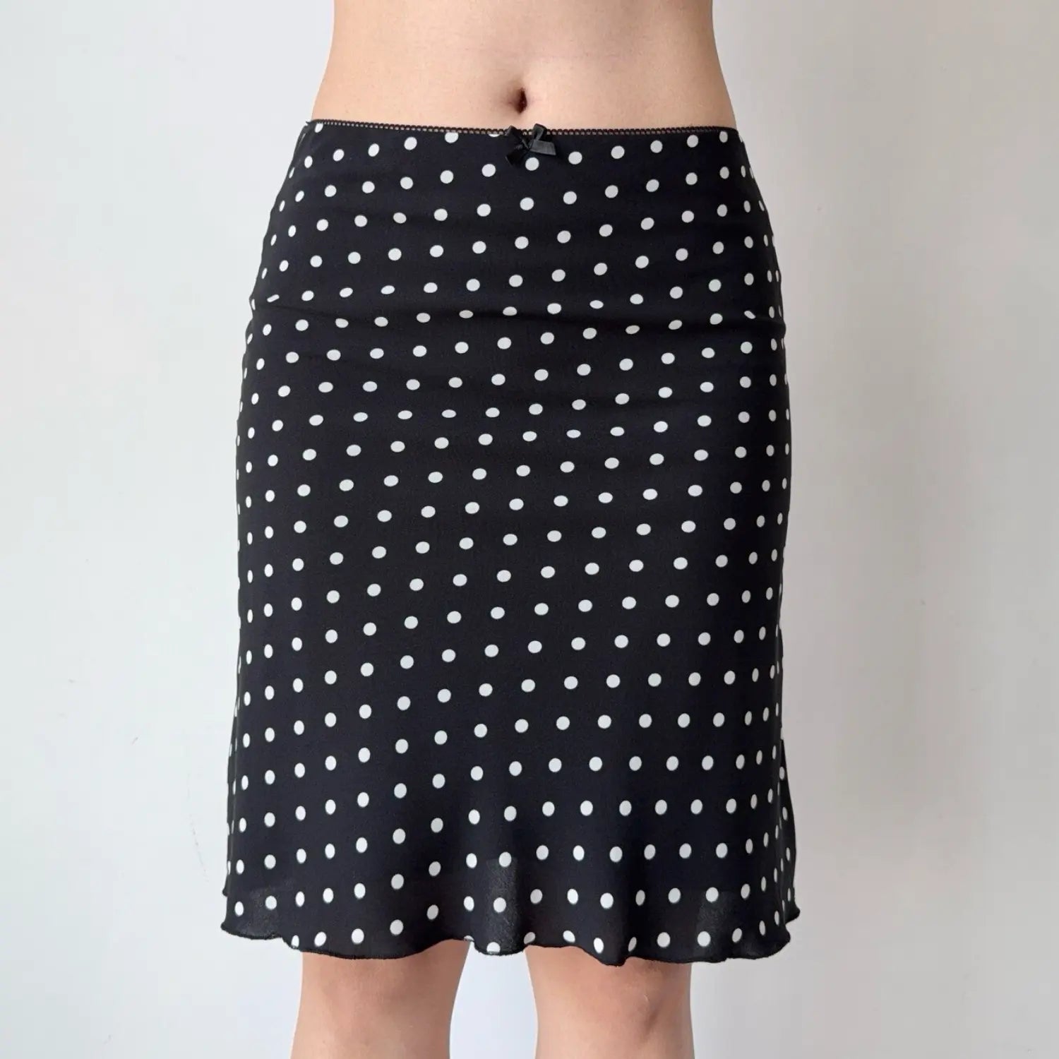 Full shot of a black polka dot chiffon midi skirt, showing the silhouette and ruffled hem