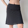 Side view of a black polka dot chiffon midi skirt, showing the flow of the fabric