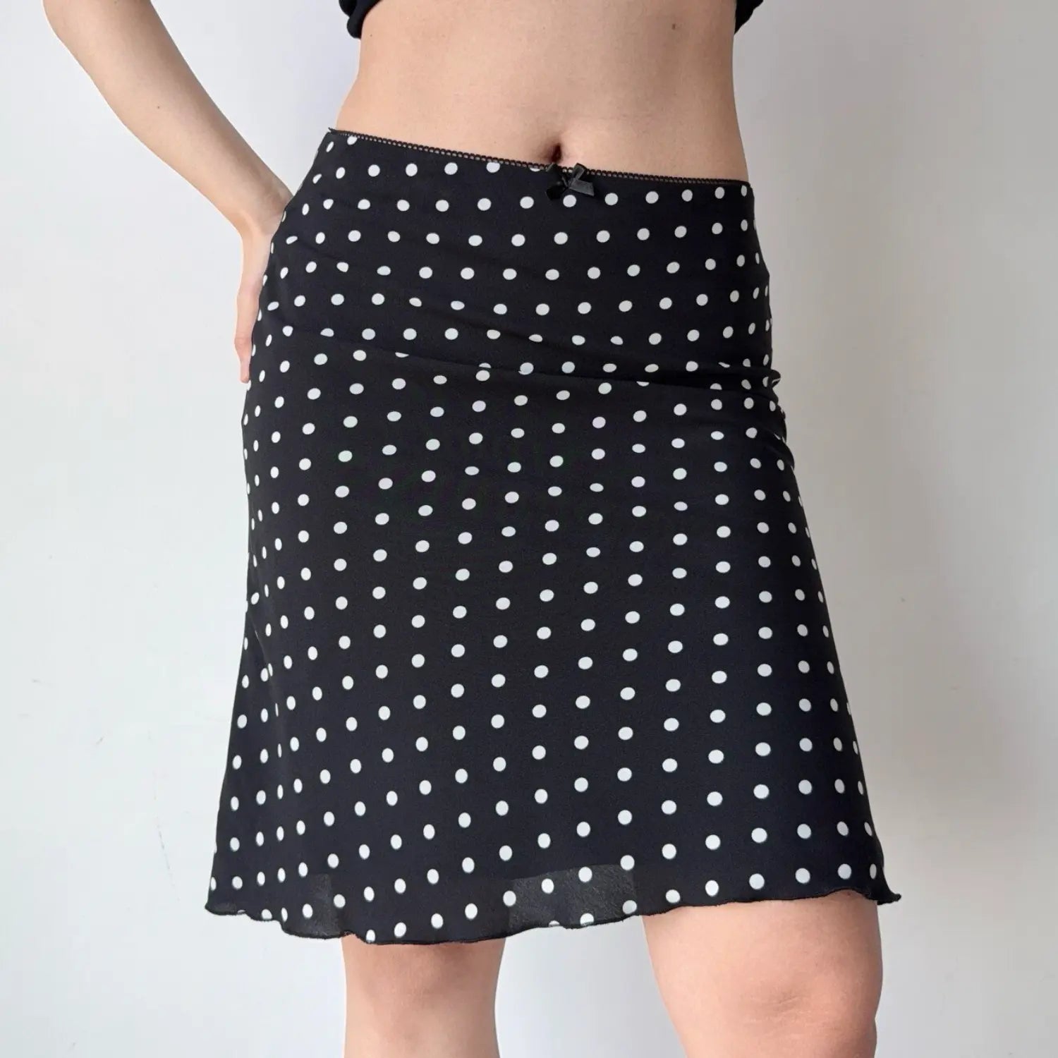 Side view of a black polka dot chiffon midi skirt, showing the flow of the fabric