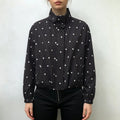 Model wearing black cropped polka dot windbreaker jacket, stand collar, relaxed fit, paired with black pants