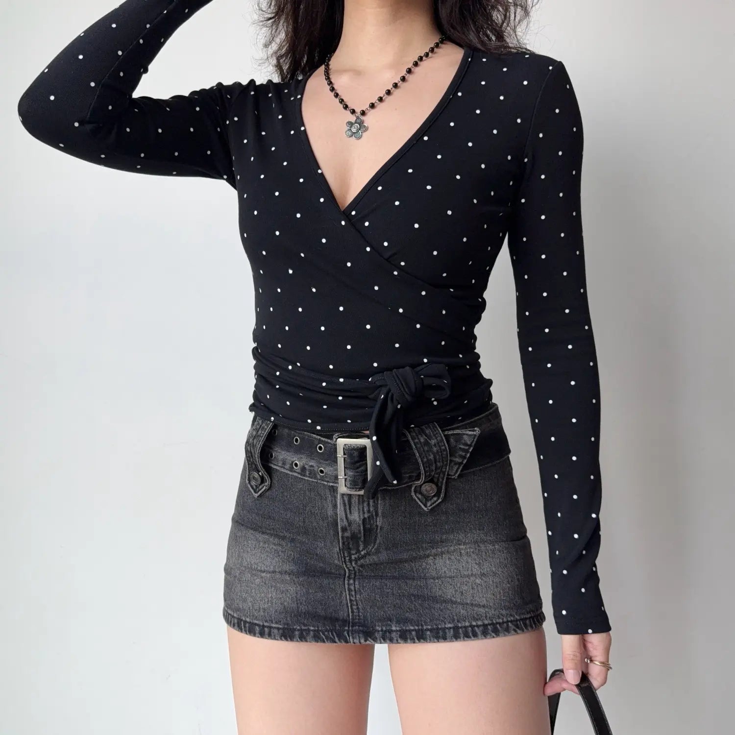 Full styling model shot black polka dot wrap v‑neck long sleeve top with side waist tie knot