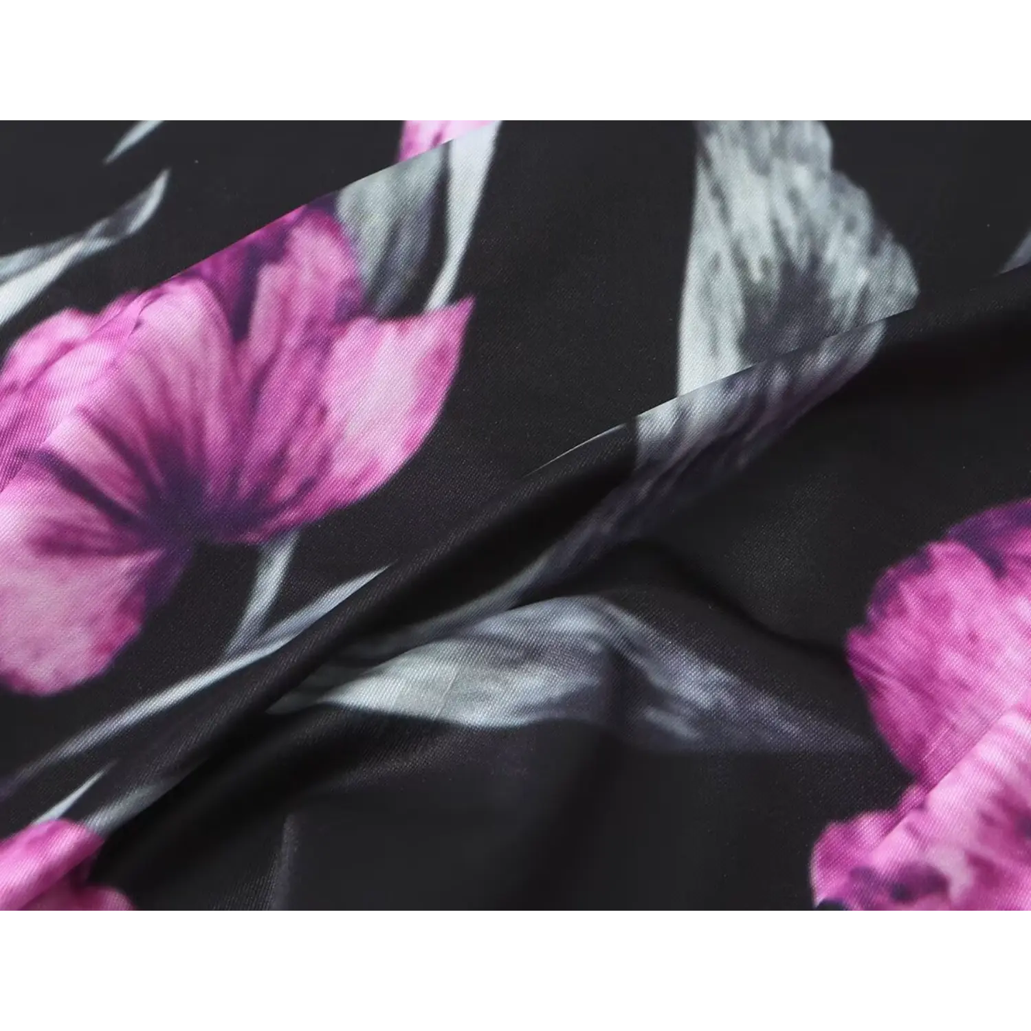 Fabric texture close‑up, black base with purple watercolor floral print