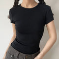 Lifestyle shot of form-fitting black ribbed crew-neck short-sleeve t-shirt, tucked into jeans