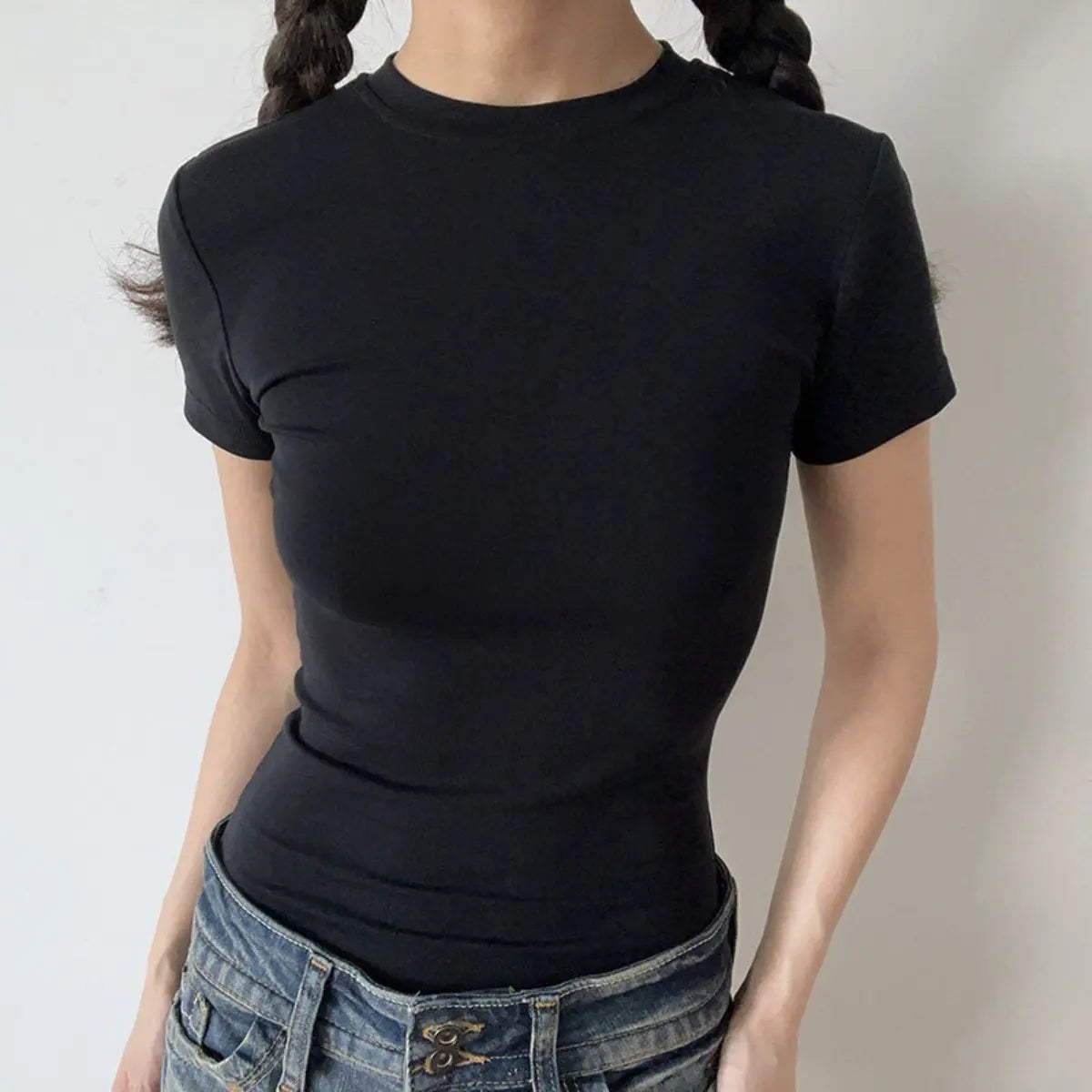Lifestyle shot of form-fitting black ribbed crew-neck t-shirt, tucked into jeans