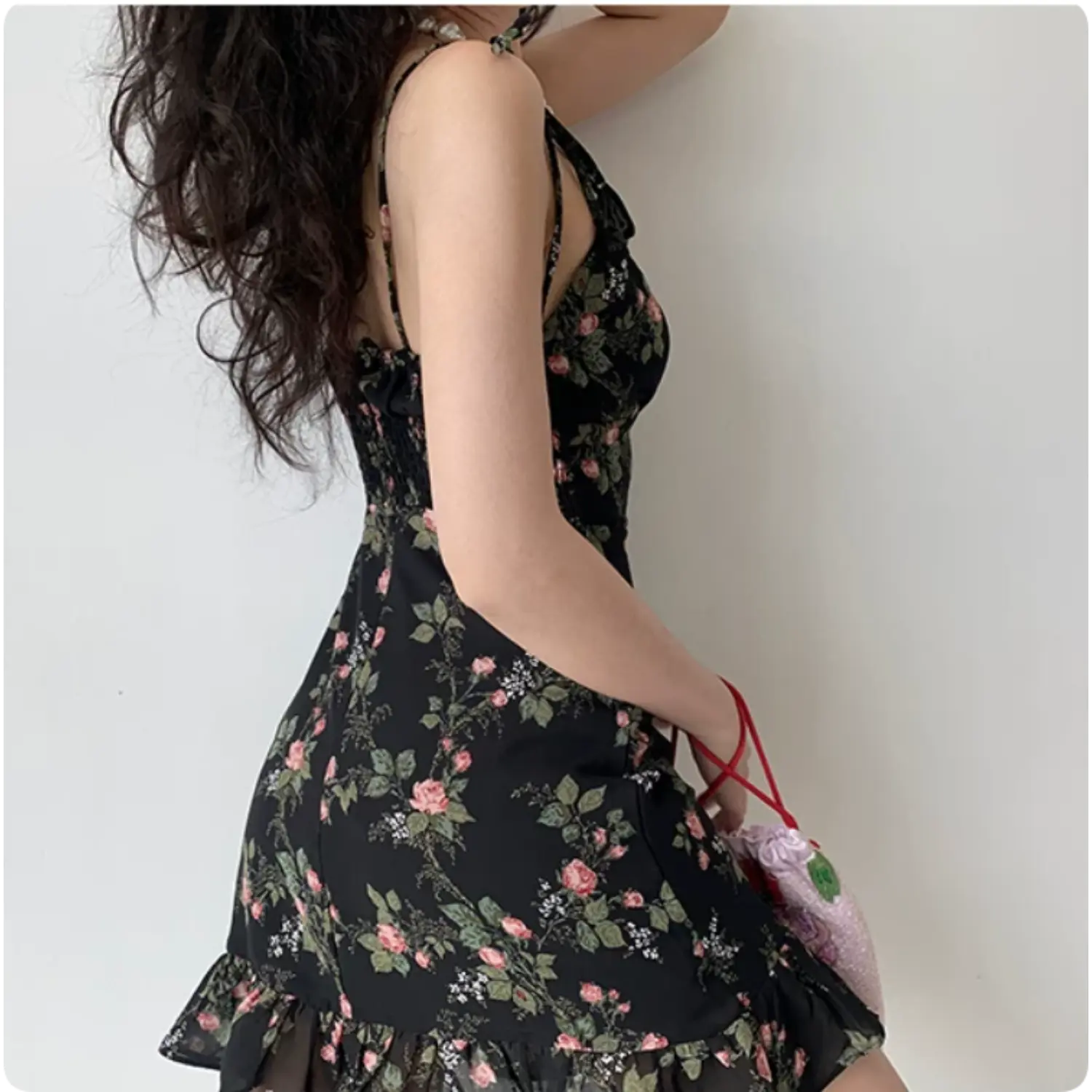 Model back three‑quarter view black rose floral mini dress tie shoulder straps smocked back panel ruffle hem chiffon dress