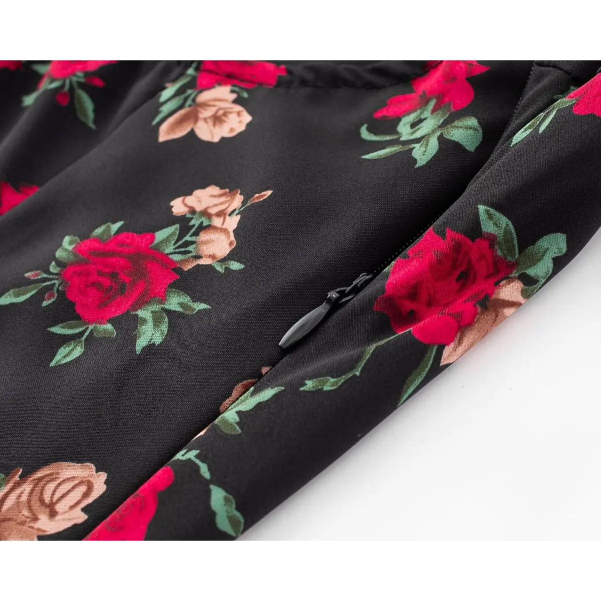 Close-up of the red and pink rose print on the black halter dress fabric.